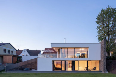 This is an example of a mid-sized contemporary two-storey stucco white house exterior in Nuremberg with a flat roof.
