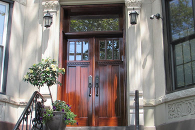 This is an example of a traditional entryway in New York with a double front door and a dark wood front door.