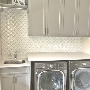 バンクーバーのカントリー風おしゃれな洗濯室 (アンダーカウンターシンク、フラットパネル扉のキャビネット、グレーのキャビネット、クオーツストーンカウンター、白い壁、クッションフロア、左右配置の洗濯機・乾燥機、マルチカラーの床、白いキッチンカウンター) の写真