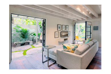 This is an example of a large modern enclosed living room in Hawaii with white walls, dark hardwood floors, no fireplace, no tv and brown floor.