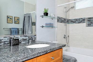 Small transitional 3/4 gray tile and glass tile porcelain tile bathroom photo in San Francisco with shaker cabinets, medium tone wood cabinets, a two-piece toilet, blue walls, an undermount sink and granite countertops