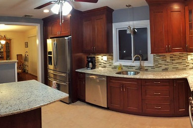 Inspiration for a small transitional l-shaped porcelain tile enclosed kitchen remodel in New York with an undermount sink, recessed-panel cabinets, medium tone wood cabinets, granite countertops, beige backsplash, ceramic backsplash, stainless steel appliances and a peninsula