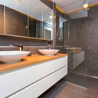 Foto di una stanza da bagno padronale minimalista di medie dimensioni con ante bianche, top in legno, doccia doppia, WC monopezzo, piastrelle grigie, piastrelle in ceramica e pavimento con piastrelle in ceramica