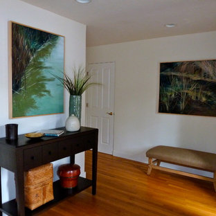 Foto på en liten eklektisk foajé, med mellanmörkt trägolv, brunt golv, beige väggar, en enkeldörr och en svart dörr