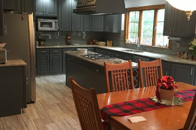 Kitchen - large porcelain tile kitchen idea in New York with a double-bowl sink, gray cabinets, granite countertops, gray backsplash, glass tile backsplash, stainless steel appliances and an island