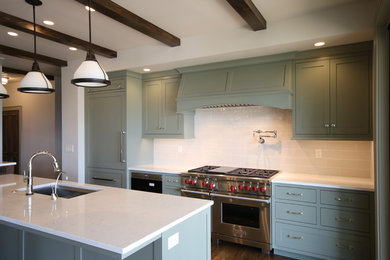 Inspiration for a mid-sized transitional l-shaped dark wood floor kitchen pantry remodel in Orange County with an undermount sink, open cabinets, green cabinets, quartz countertops, white backsplash, glass tile backsplash, stainless steel appliances and an island