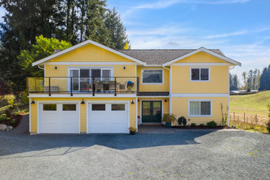 Example of a farmhouse yellow two-story concrete fiberboard and shingle house exterior design in Vancouver with a shingle roof and a gray roof