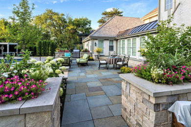 Large traditional backyard patio in Chicago with natural stone pavers and no cover.