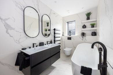 Medium sized contemporary family bathroom in Manchester with recessed-panel cabinets, black cabinets, a freestanding bath, a walk-in shower, a wall mounted toilet, white tiles, porcelain tiles, white walls, porcelain flooring, a wall-mounted sink, white floors, an open shower, a wall niche, double sinks and a floating vanity unit.