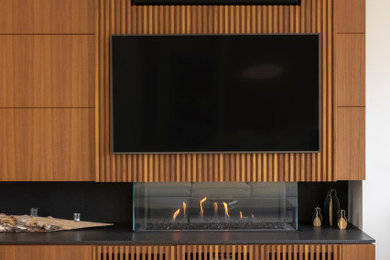 Modernes Wohnzimmer mit schwarzer Wandfarbe, Betonboden, Gaskamin, Kaminumrandung aus Holz, Multimediawand, grauem Boden und Wandpaneelen in Vancouver