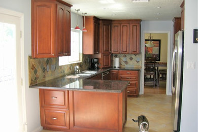 Mid-sized elegant l-shaped ceramic tile and multicolored floor open concept kitchen photo in Los Angeles with an undermount sink, raised-panel cabinets, granite countertops, multicolored backsplash, slate backsplash, stainless steel appliances, a peninsula, multicolored countertops and medium tone wood cabinets