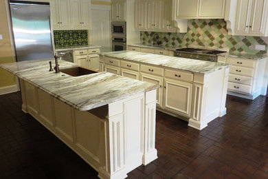 Inspiration for a large timeless l-shaped brick floor eat-in kitchen remodel in Dallas with a farmhouse sink, raised-panel cabinets, white cabinets, granite countertops, green backsplash, ceramic backsplash, stainless steel appliances and two islands