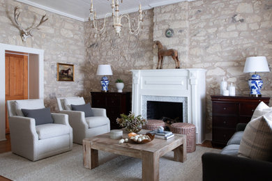 Modelo de salón clásico con paredes beige, suelo de madera en tonos medios, todas las chimeneas y suelo marrón