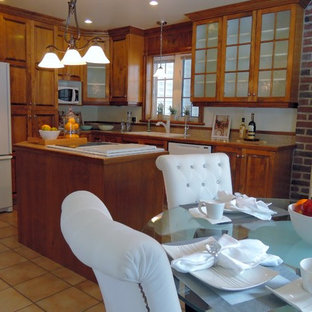 На фото: маленькая линейная кухня в классическом стиле с обеденным столом, двойной раковиной, фасадами в стиле шейкер, фасадами цвета дерева среднего тона, столешницей из кварцита, белым фартуком, полом из терракотовой плитки, островом, белой техникой, оранжевым полом и бежевой столешницей с