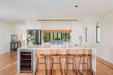 Inspiration for a mid-sized contemporary galley eat-in kitchen in Brisbane with an undermount sink, quartz benchtops, metallic splashback, mirror splashback, stainless steel appliances, light hardwood floors and with island.