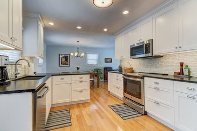 Eat-in kitchen - transitional medium tone wood floor eat-in kitchen idea in St Louis with an undermount sink, white cabinets, granite countertops and black countertops
