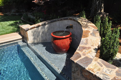 Photo of a large mediterranean backyard rectangular lap pool in Sacramento with a water feature and stamped concrete.
