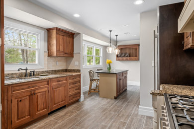 Mid-sized transitional galley ceramic tile kitchen photo in Philadelphia with a double-bowl sink, medium tone wood cabinets, granite countertops, beige backsplash, ceramic backsplash, stainless steel appliances and an island