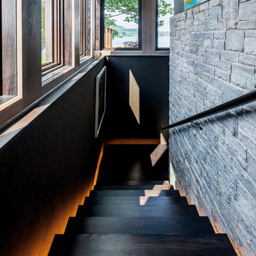 Custom staircase disappears behind the central fireplace, featuring LED lighting
