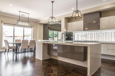 Large contemporary single-wall eat-in kitchen in Melbourne with flat-panel cabinets, white cabinets, white splashback, with island and multi-coloured benchtop.