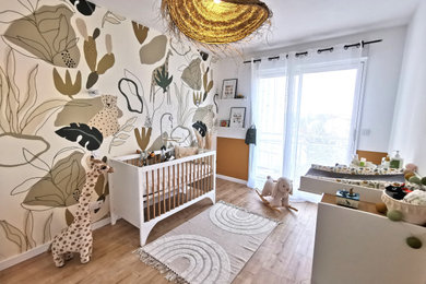 Exemple d'une chambre de bébé neutre exotique de taille moyenne avec un mur vert, un sol en contreplaqué, un sol beige et du papier peint.