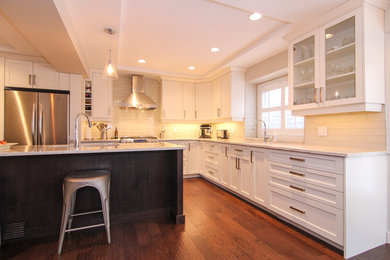 Eat-in kitchen - large transitional u-shaped dark wood floor and brown floor eat-in kitchen idea in Calgary with an undermount sink, recessed-panel cabinets, white cabinets, quartzite countertops, white backsplash, subway tile backsplash, stainless steel appliances, an island and white countertops