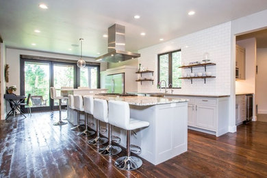 This is an example of a large country single-wall eat-in kitchen in Other with a farmhouse sink, shaker cabinets, white cabinets, granite benchtops, red splashback, subway tile splashback, stainless steel appliances, dark hardwood floors, with island and brown floor.