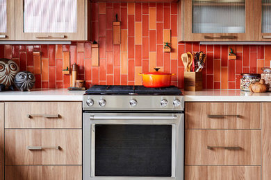 Mid-sized trendy galley porcelain tile and gray floor enclosed kitchen photo in Los Angeles with a single-bowl sink, glass-front cabinets, medium tone wood cabinets, quartz countertops, orange backsplash, ceramic backsplash, stainless steel appliances and no island
