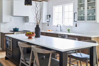 Example of a farmhouse l-shaped light wood floor, beige floor and exposed beam kitchen design in Chicago with an undermount sink, shaker cabinets, dark wood cabinets, white backsplash, stainless steel appliances, an island and white countertops