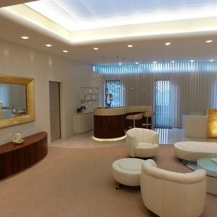 Diseño de salón para visitas mediterráneo con paredes beige, suelo de contrachapado y televisor retractable