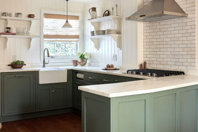 Example of a mid-sized transitional u-shaped dark wood floor and brown floor enclosed kitchen design in New York with a farmhouse sink, shaker cabinets, green cabinets, marble countertops, yellow backsplash, wood backsplash, paneled appliances and white countertops