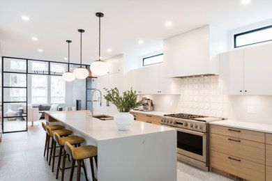 Zweizeilige Moderne Küche mit Unterbauwaschbecken, flächenbündigen Schrankfronten, hellbraunen Holzschränken, Küchengeräten aus Edelstahl, Kücheninsel, grauem Boden und weißer Arbeitsplatte in Vancouver