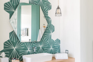 Cette photo montre une salle de bain méditerranéenne avec un carrelage vert, un mur blanc, une vasque, un plan de toilette en bois et un sol gris.