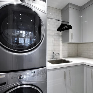 トロントの中サイズのコンテンポラリースタイルのおしゃれな洗濯室 (アンダーカウンターシンク、フラットパネル扉のキャビネット、グレーのキャビネット、ラミネートカウンター、グレーの壁、磁器タイルの床、上下配置の洗濯機・乾燥機、グレーの床) の写真