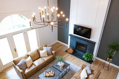 Family room - large transitional open concept light wood floor, brown floor and vaulted ceiling family room idea in Chicago with black walls, a standard fireplace, a stone fireplace and a wall-mounted tv