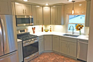 This is an example of a small transitional l-shaped eat-in kitchen in Denver with an undermount sink, shaker cabinets, green cabinets, granite benchtops, white splashback, glass tile splashback, stainless steel appliances, no island, porcelain floors and red floor.