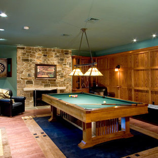 Inspiration for a medium sized classic walk-out basement in Other with green walls, medium hardwood flooring, a standard fireplace and a stone fireplace surround.