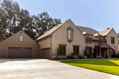 Пример оригинального дизайна: большой, двухэтажный, кирпичный, коричневый частный загородный дом в классическом стиле с крышей из гибкой черепицы и коричневой крышей