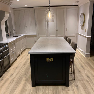 Dark blue kitchen island with neutral coloured cabinets and full length larder
