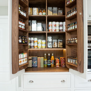 Cette image montre une arrière-cuisine traditionnelle avec un placard à porte shaker, des portes de placard blanches et béton au sol.