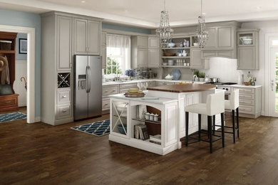 Large elegant l-shaped dark wood floor and brown floor kitchen pantry photo in Other with an undermount sink, raised-panel cabinets, gray cabinets, solid surface countertops, white backsplash, stainless steel appliances and an island