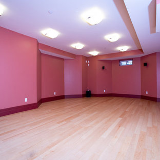 Photo of a large traditional fully buried basement in Boston with pink walls and light hardwood flooring.