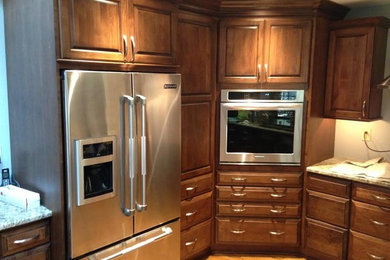 Mid-sized elegant light wood floor kitchen photo in Baltimore with raised-panel cabinets, medium tone wood cabinets, granite countertops and stainless steel appliances