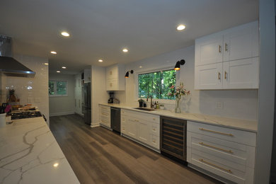 Example of a mid-sized minimalist galley gray floor and bamboo floor eat-in kitchen design in Atlanta with white cabinets, white backsplash, stainless steel appliances and white countertops