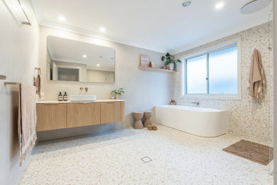 Expansive modern kids bathroom in Sydney with flat-panel cabinets, light wood cabinets, a corner tub, an open shower, a two-piece toilet, beige tile, a vessel sink, multi-coloured floor, an open shower, white benchtops, a niche, a single vanity and a floating vanity.