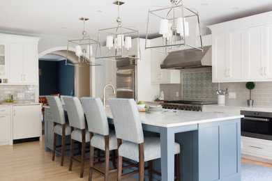 Large beach style light wood floor eat-in kitchen photo in Portland Maine with a single-bowl sink, shaker cabinets, white cabinets, marble countertops, gray backsplash, subway tile backsplash, stainless steel appliances, an island and white countertops