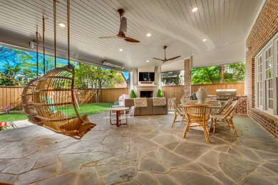 Inspiration for a large contemporary backyard patio in Dallas with an outdoor kitchen, natural stone pavers and a roof extension.