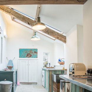 This is an example of a medium sized rustic galley laundry cupboard in Devon with a belfast sink, zinc worktops, white walls, limestone flooring, a side by side washer and dryer and grey floors.