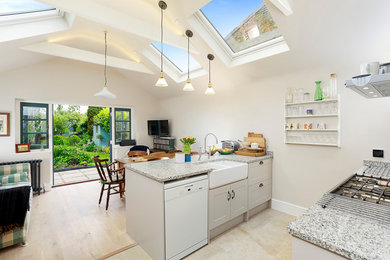 Inspiration for a large bohemian galley open plan kitchen in Kent with a belfast sink, shaker cabinets, beige cabinets, granite worktops, grey splashback, stone slab splashback, stainless steel appliances, travertine flooring, no island, beige floors and grey worktops.