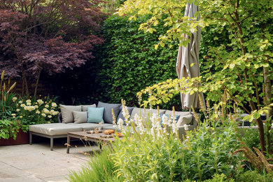 Design ideas for a medium sized contemporary back formal full sun garden for summer in London with a raised bed, natural stone paving and a metal fence.